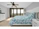 Bright bedroom with a ceiling fan, balcony access, and colorful bedding at 6415 Midnight Pass Rd # 909, Sarasota, FL 34242