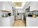 Modern kitchen with stainless appliances, white cabinets, and ceiling fan at 6415 Midnight Pass Rd # 909, Sarasota, FL 34242