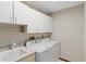 Bright laundry room featuring a washing machine, dryer, utility sink, and upper cabinets at 6427 Canary St, Sarasota, FL 34241