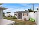 A tidy backyard featuring a storage shed, white vinyl fence, landscaping, and green kayak at 648 Cypress Rd, Venice, FL 34293
