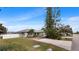 A charming single-story home with a manicured lawn, driveway and mature trees under a bright, clear sky at 648 Cypress Rd, Venice, FL 34293