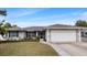 Charming single-story home boasts a lush front yard with vibrant landscaping and an attached two-car garage at 648 Cypress Rd, Venice, FL 34293