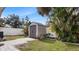 Backyard shed with gray doors, surrounding tropical landscaping and a brick pathway at 648 Cypress Rd, Venice, FL 34293