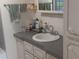 Close-up of a bathroom sink featuring an oval white sink, grey countertop and decorative vanity with storage at 722 S Green Cir, Venice, FL 34285