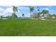 Spacious common area with lush green grass, a lake view, and flagpoles in a serene community setting at 891 Grado Dr, Venice, FL 34285