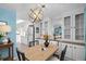 Dining area with a modern chandelier, white cabinets, and a wooden table with black chairs at 891 Grado Dr, Venice, FL 34285
