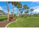 Beautifully landscaped grounds with well-manicured lawns, tropical plants, and mature palm trees at 891 Grado Dr, Venice, FL 34285