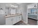 Bathroom features dual sinks, white cabinetry, and a doorway view to main bedroom at 8969 Mondial Ct, Venice, FL 34293