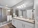 Well-lit bathroom with double sinks, white cabinets, and a glass-enclosed shower at 8969 Mondial Ct, Venice, FL 34293