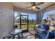 Relaxing screened patio featuring comfortable blue seating, a ceiling fan, and a view of the lake at 8969 Mondial Ct, Venice, FL 34293