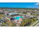 Aerial view of the community pool with surrounding homes, palm trees, and a blue sky at 8969 Mondial Ct, Venice, FL 34293