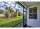 Relaxing screened-in back porch overlooking a lush green yard with palm trees and blue skies at 9916 Bright Water Dr, Englewood, FL 34223
