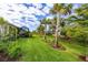 Large backyard showcasing healthy green grass, privacy landscaping, and mature palm trees at 9916 Bright Water Dr, Englewood, FL 34223