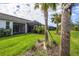 Wide shot of the backyard, featuring healthy green grass, lush landscaping, and a screened lanai at 9916 Bright Water Dr, Englewood, FL 34223
