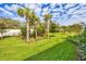 Expansive backyard featuring healthy green grass, lush landscaping, and mature palm trees at 9916 Bright Water Dr, Englewood, FL 34223