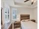 Comfortable main bedroom featuring a bed, nightstands, tray ceiling, and shuttered windows at 9916 Bright Water Dr, Englewood, FL 34223