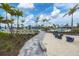 Community pool area features sandy lounge, seating, and palm trees under a sunny, partly cloudy sky at 9916 Bright Water Dr, Englewood, FL 34223