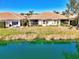 Backyard view of home with a patio, overlooking lush lawn and a serene pond with clear, teal-colored water at 1018 Yosemite Dr, Englewood, FL 34223
