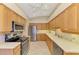 Spacious kitchen featuring wood cabinetry, stainless steel appliances, tiled floors, and a modern ceiling fan at 1018 Yosemite Dr, Englewood, FL 34223