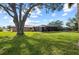 Expansive backyard featuring lush green grass, a large shade tree, and a screened lanai for outdoor enjoyment at 107 Corot Dr, Nokomis, FL 34275