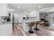 Modern white kitchen with breakfast bar seating, stainless steel appliances, and views of the living area at 107 Corot Dr, Nokomis, FL 34275