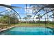 Screened-in outdoor swimming pool with clear water and lush green backyard under a blue sky at 107 Corot Dr, Nokomis, FL 34275
