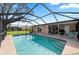 Back view of the enclosed pool area, showing pool steps and an outdoor seating area at 107 Corot Dr, Nokomis, FL 34275