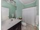 Bright bathroom with fresh mint green walls, white fixtures, and shower featuring a white curtain at 10768 Trophy Dr, Englewood, FL 34223