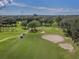 Aerial view of lush golf course featuring manicured greens, sand traps, and fairways amidst mature trees at 10768 Trophy Dr, Englewood, FL 34223