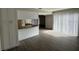 Sunlit living room with wood-look floors and a kitchen view with white vertical blinds at 1190 Longfellow Way # 135C, Sarasota, FL 34243