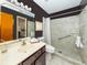 Cozy bathroom featuring tiled walk-in shower, dark accent wall, and neutral vanity at 1200 Yawl Way, Venice, FL 34285