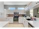 Well-lit kitchen with stainless steel appliances, white cabinets, tile backsplash, and lots of countertop space at 161 Valencia Lakes Dr, Venice, FL 34292