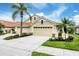 Charming home featuring a three-car garage, lush landscaping, and mature palm trees at 1697 San Silvestro Dr, Venice, FL 34285