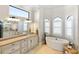 Bright bathroom featuring a soaking tub, travertine floors, custom cabinets, and three arched windows at 19227 Palmdale Ct, Port Charlotte, FL 33948