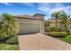 Well-maintained home with a tile roof, lush landscaping, and a brick driveway leading to a two-car garage at 19340 Bluff Dr, Venice, FL 34292