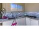 Well-designed outdoor kitchen featuring a stainless steel sink, cooktop, stylish backsplash and granite countertop at 19340 Bluff Dr, Venice, FL 34292