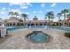 Community pool with a jacuzzi, lounge chairs, and umbrellas surrounded by tropical landscaping and clubhouse at 20235 Pezzana Dr, Venice, FL 34292