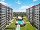 Condominium buildings overlooking a pool with lounge chairs surrounded by a green lawn at 232 Saint Augustine Ave # 207, Venice, FL 34285