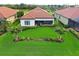 Aerial view of the backyard featuring lush green grass, privacy landscaping, and a screened in lanai at 23415 Waverly Cir, Venice, FL 34293