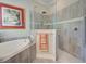Bathroom featuring a soaking tub, tiled surround, and corner glass shower at 23415 Waverly Cir, Venice, FL 34293