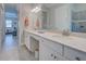 Bright bathroom with a double vanity, white cabinetry, and tiled floor at 23415 Waverly Cir, Venice, FL 34293