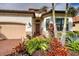 Home exterior with a red tile roof, brick driveway and walkway, and colorful tropical landscaping at 23415 Waverly Cir, Venice, FL 34293