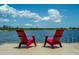 Inviting waterfront view with bright red Adirondack chairs and calming blue waters at 23415 Waverly Cir, Venice, FL 34293