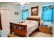 Bright bedroom with a beautiful wood frame bed, soft blue curtains, and coastal-themed decor at 23495 Altman Ave, Punta Gorda, FL 33980