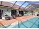 Stunning pool area with a screened lanai, brick pavers, lounge chairs, and a lush tropical landscape, ideal for relaxation at 23495 Altman Ave, Punta Gorda, FL 33980