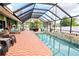 Beautiful pool area with a screened lanai, brick pavers, and comfortable seating perfect for relaxation and entertaining at 23495 Altman Ave, Punta Gorda, FL 33980