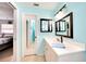A serene bathroom with blue walls features a vanity, mirror, lights, toilet, and glass shower at 2783 Biscayne Dr, North Port, FL 34287