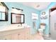 A serene bathroom with blue walls features a vanity, mirror, lights, toilet, and glass shower at 2783 Biscayne Dr, North Port, FL 34287