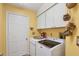 Laundry room with a washer and dryer, cabinets, and a white door at 311 Pembroke Dr # 217, Venice, FL 34293
