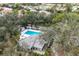 Aerial view of a community pool featuring ample seating, mature trees, and a bright blue swimming pool at 311 Pembroke Dr # 217, Venice, FL 34293